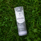 sfeerfoto van een Ben & Anna Highland Breeze Sensitive deodorantstick liggend in fris groen gras. De grijs-witte kartonnen verpakking met botanische details en natuurlijke claims is scherp in beeld, terwijl het omliggende gras zorgt voor een natuurlijke, duurzame en premium uitstraling