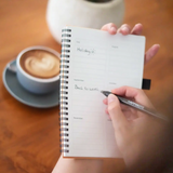 Herbruikbaar Happinote notitieboek gebruikt voor planning en notities aan tafel met koffie